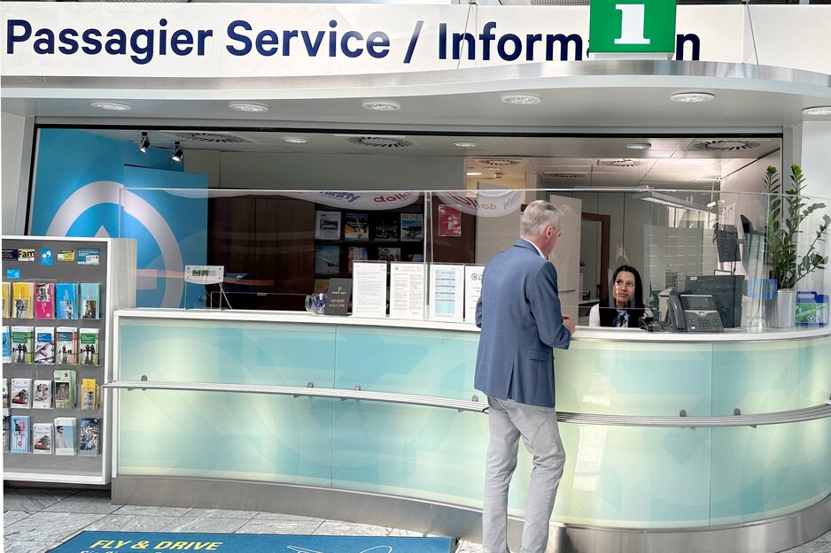 Passagier im Gespräch mit Mitarbeiterin des PSC am Counter | © Linz Airport