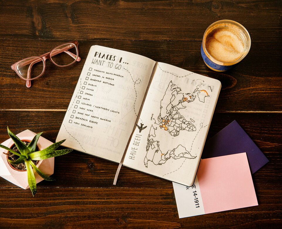 Urlaubsplaner mit To-Do-Liste und Landkarte auf Tisch | © Unsplash