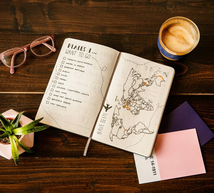 Urlaubsplaner mit To-Do-Liste und Landkarte auf Tisch | © Unsplash