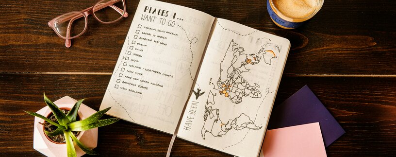 Urlaubsplaner mit To-Do-Liste und Landkarte auf Tisch | © Unsplash
