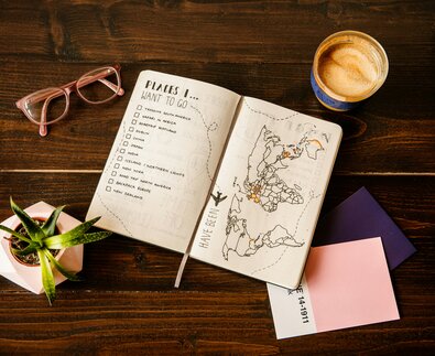 Urlaubsplaner mit To-Do-Liste und Landkarte auf Tisch | © Unsplash