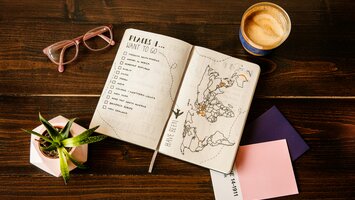 Urlaubsplaner mit To-Do-Liste und Landkarte auf Tisch | © Unsplash