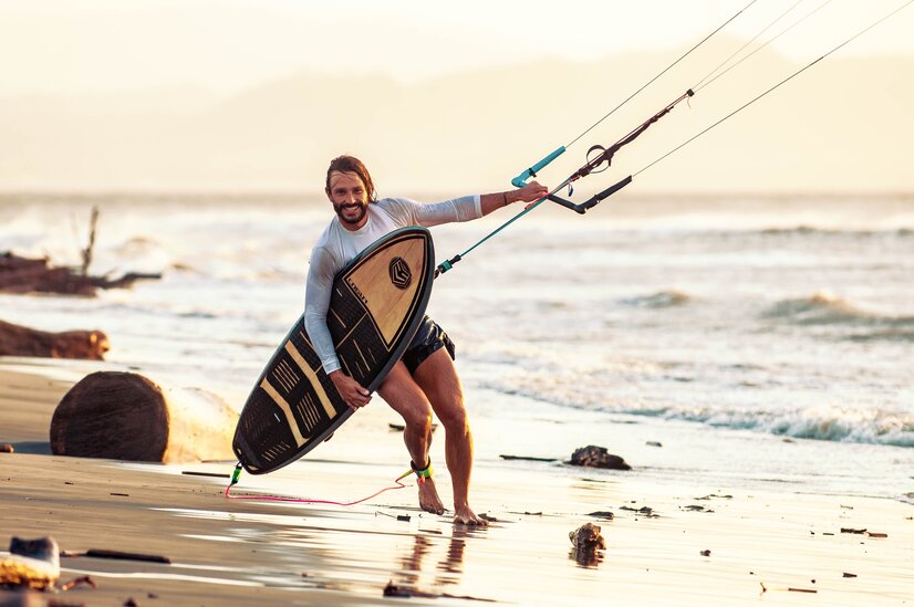 Mann am Strand mit Skiteboard | © Foto von Cogua Kiteboading von Pexels Mann am Strand mit Skiteboard | © Foto von Cogua Kiteboading von Pexels