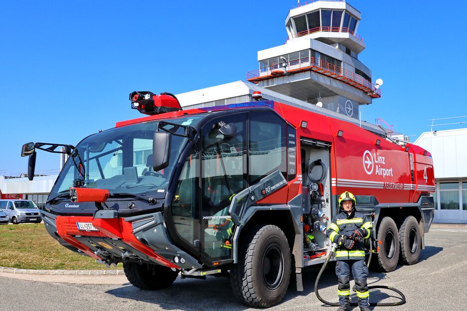 Feuerwehrmitarbeiter mit Schlauch neben Panther vor Tower | © Linz Airport