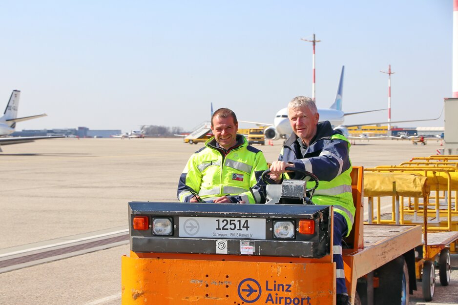 Zwei Vorfeldmitarbeiter  auf E-Karren beim Vorbeifahren | © Linz Airport