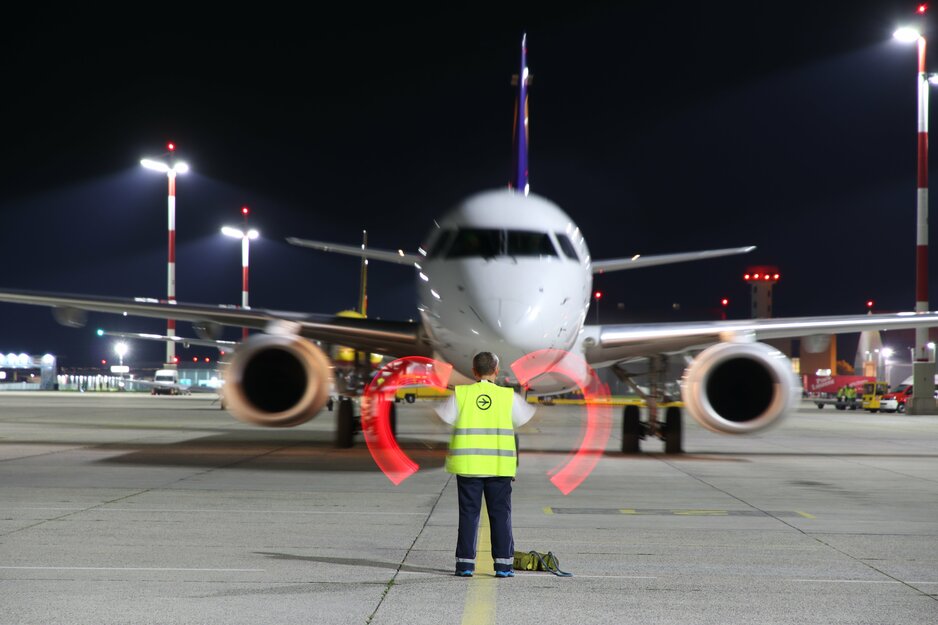 Vorfeldmitarbeiter mit Leuchtstäben beim Einweisen eines Flugzeuges am Abend | © Linz Airport