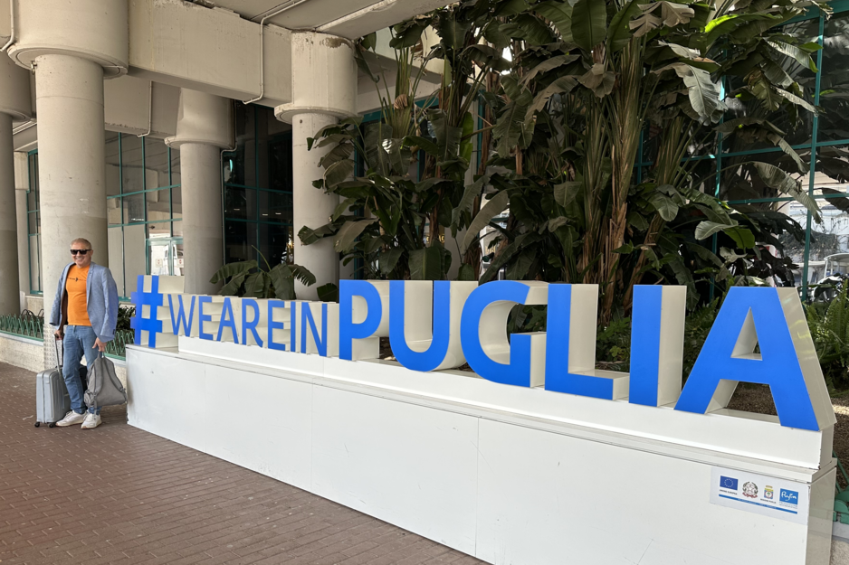 We are in Puglia Schriftzug mit Mann mit Koffer in der Hand | © Linz Airport