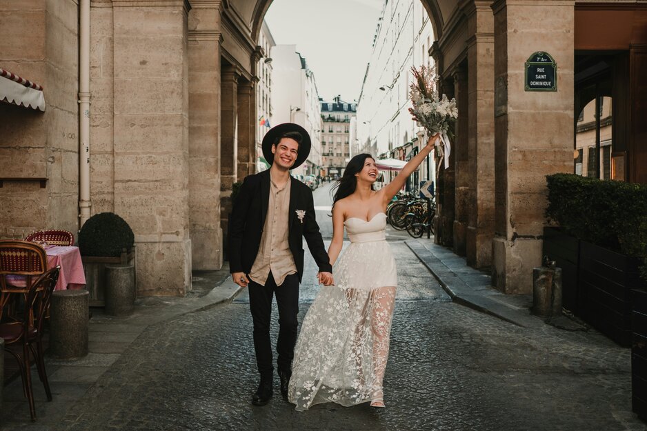 Fröhliches, junges, legeres Hochzeitspaar vor Torbogen | © Unsplash