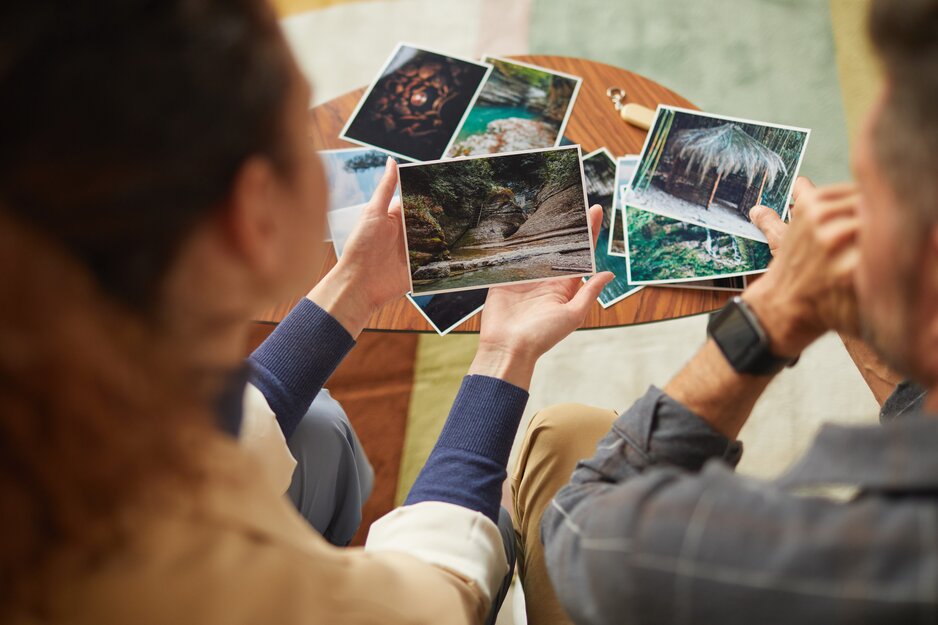Paar hält Urlaubsbilder in der Hand und betrachtet diese | © Envato Elements