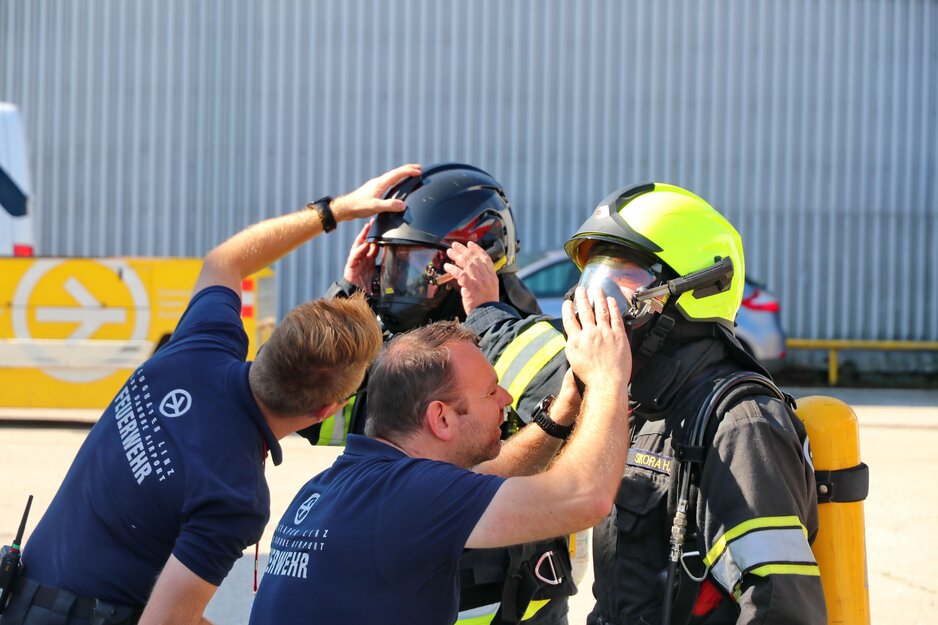 Zwei Feuerwehrleute kontrollieren die Schutzhelme von zwei anderen | © Linz Airport