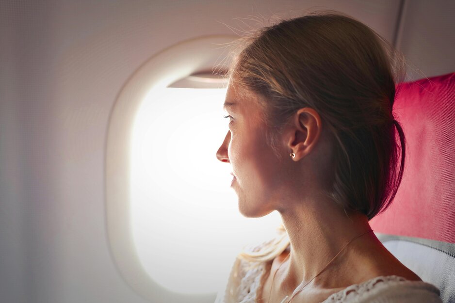Junge Frau blickt durch Flugzeugfenster | © Pexels Junge Frau blickt durch Flugzeugfenster | © Pexels
