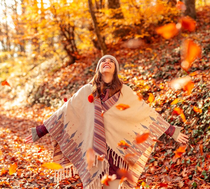 Glückliche junge Frau wirft bunte Herbstblätter im Wald in die Luft | © Envato Elements