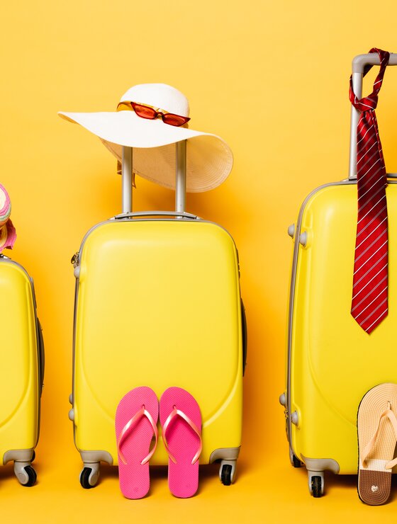 Gelbes Kofferset mit Accessoires vor gelben Hintergrund | © Envato