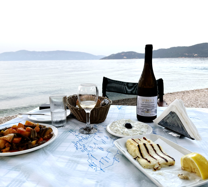 Tisch am Strand von Kefalonia gedeckt mit Tzatziki, gegrillten Käse und Gemüse und Wein | © Linz Airport
