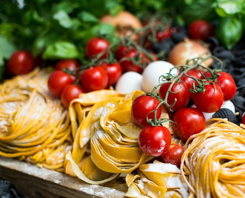 Gelbe ungekochte Nudeln und Kirschtomaten | © Unsplash