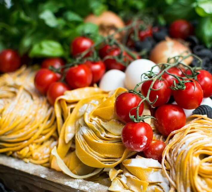 Gelbe ungekochte Nudeln und Kirschtomaten | © Unsplash