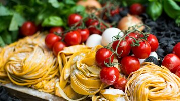 Gelbe ungekochte Nudeln und Kirschtomaten | © Unsplash