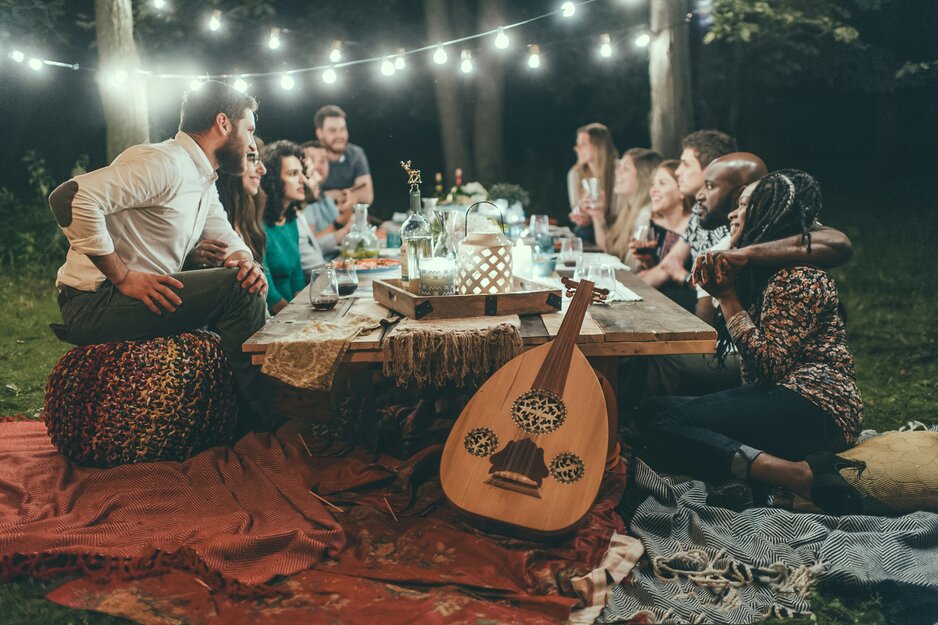 Gruppe junger Menschen an Holztisch im Garten bei Nacht | © Unsplash