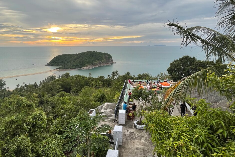 Blick von oben auf die Terrasse eines kleinen Restaurants mit Gästen und auf das Meer mit kleiner Insel in Koh Pangan | © Linz Airport