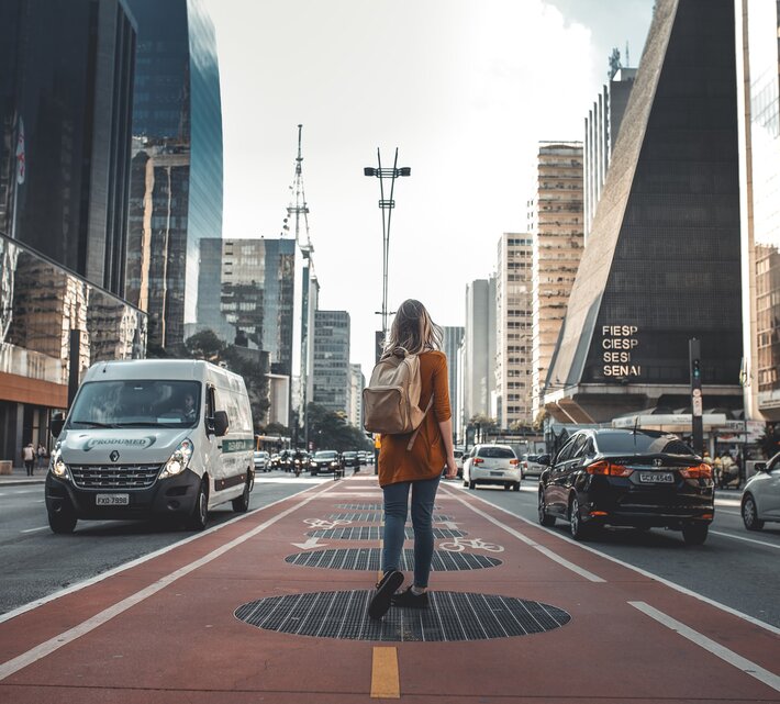 Junge Frau mit Rucksack wandert durch die City | © Guilherme Stecanella Unsplash