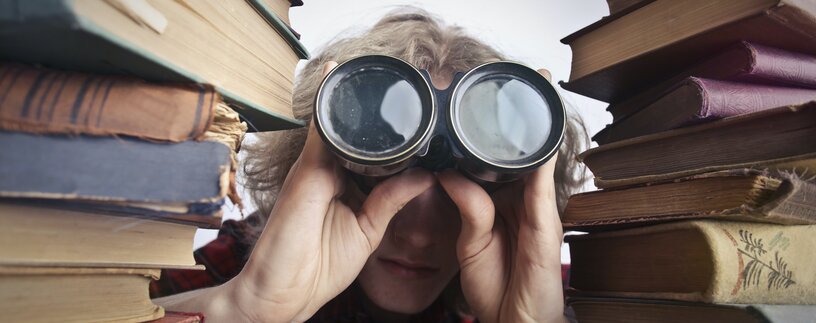 Mann blickt mit Fernglas durch Bücker | © Andrea Piacquadio Pexels