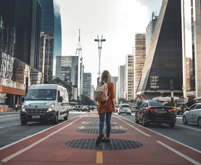 Junge Frau mit Rucksack wandert durch die City | © Guilherme Stecanella Unsplash