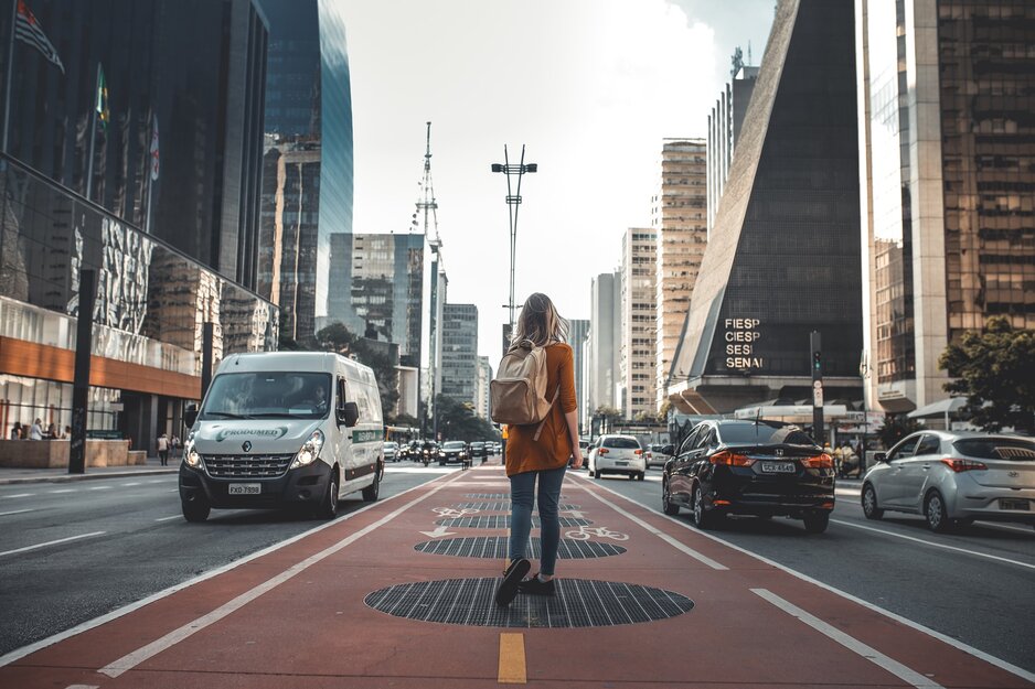 Junge Frau mit Rucksack wandert durch die City | © Guilherme Stecanella Unsplash