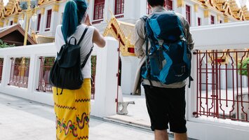 Zwei Touristen mit Rucksäcken vor indonesischem Tempel | © George Pak Pexels