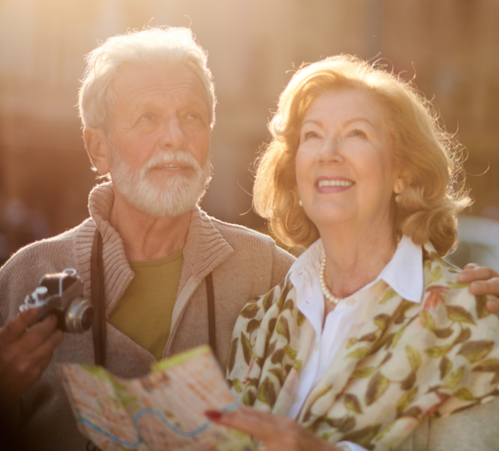 Älteres Paar mit Kamera und Stadtführer lächelt glücklich im Sonnenschein | © Canvas