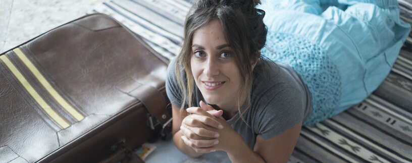 Junge Frau am Boden liegend und Reiseunterlagen betrachtend | © Envato Elements
