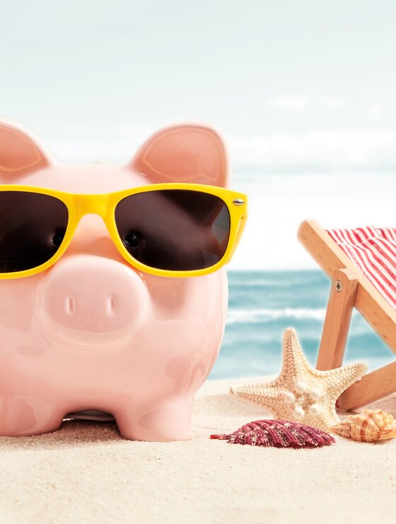Pinkes Sparschwein mit gelber Sonnenbrille am Strand | © Adobe Stock