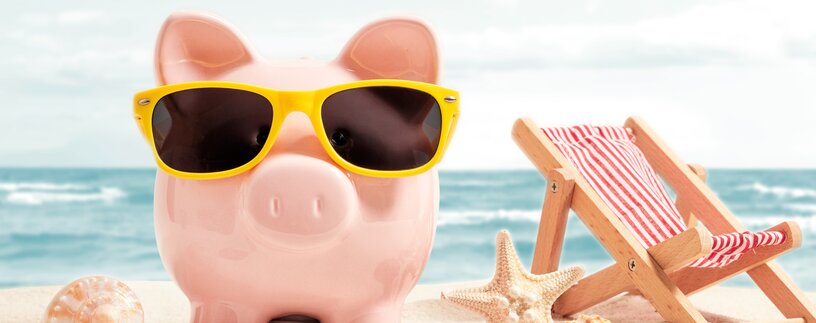 Pinkes Sparschwein mit gelber Sonnenbrille am Strand | © Adobe Stock