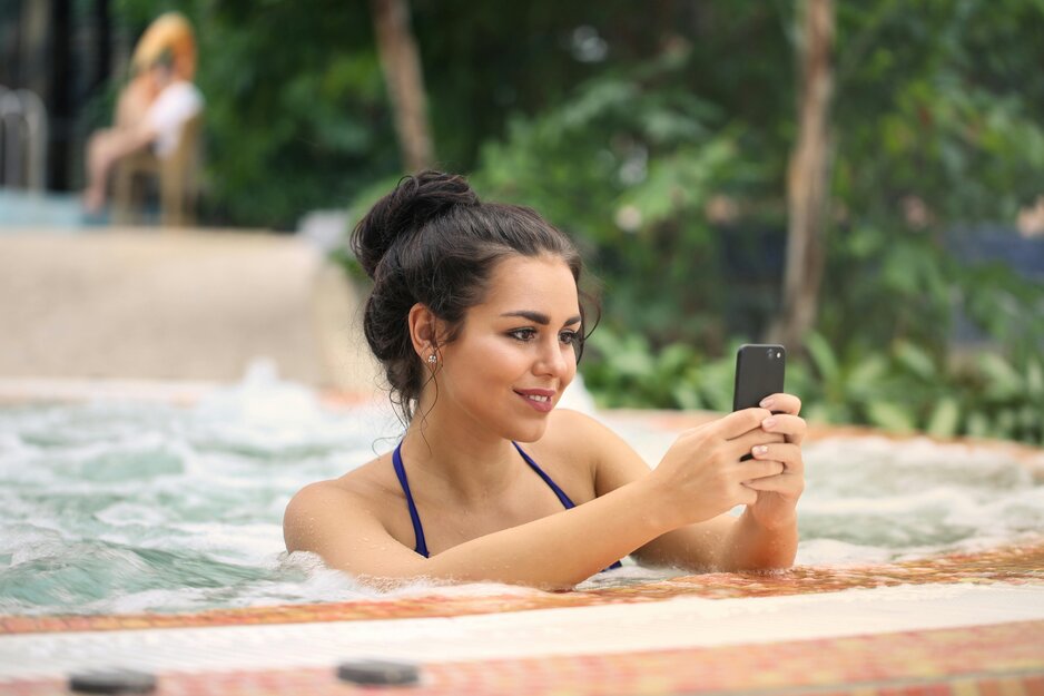 Junge Frau schreibt am Handy in Whirlpool  | © Pexels