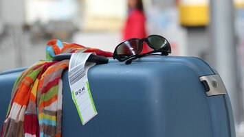 Blauer Koffer mit Sonnenbrille und buntem Tuch mit TAG nach Rom | © Flughafen Linz