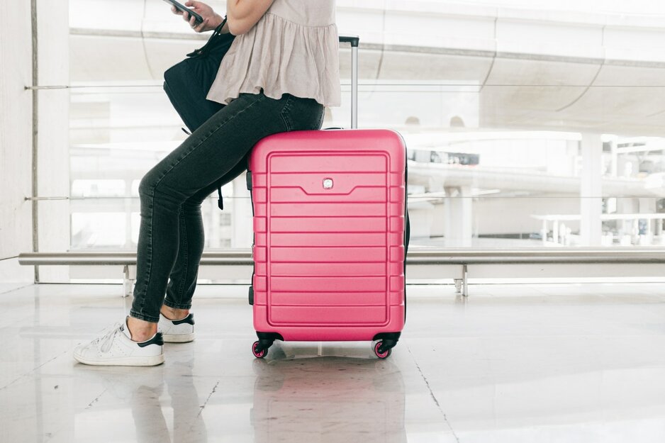Frau sitzt auf rosafarbenem Koffer | © Daria Shevtsova Pexels