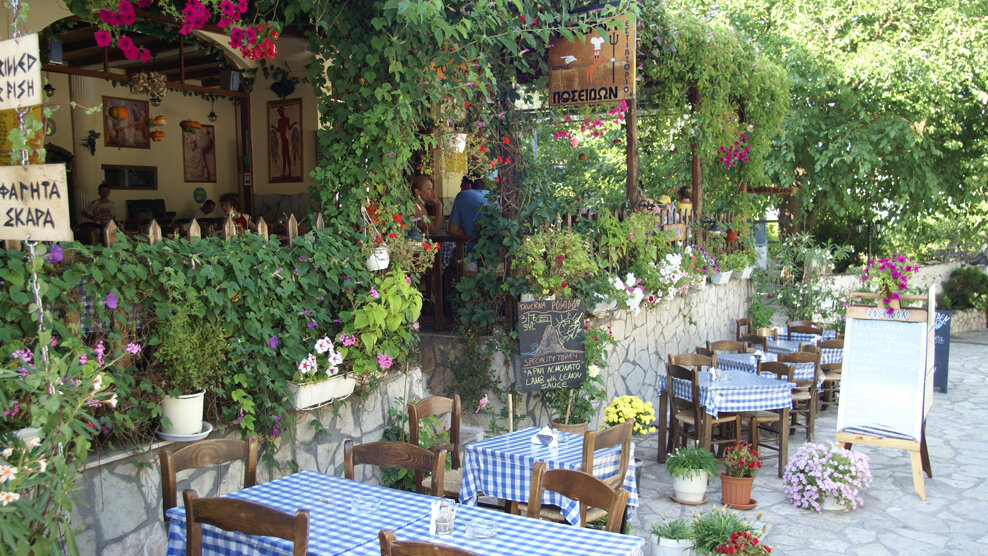 typische griechische Taverne mit blau karierten Tischtüchern und vielen grünen Pflanzen | © Rhomberg Reisen
