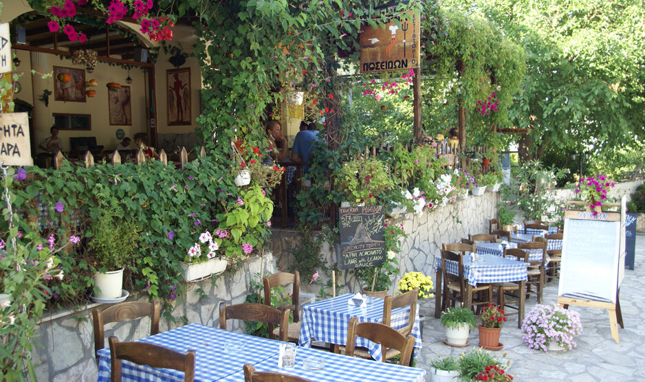 typische griechische Taverne mit blau karierten Tischtüchern und vielen grünen Pflanzen | © Rhomberg Reisen